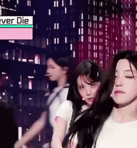 a group of young women are dancing on a stage with a sign that says ever die in the background