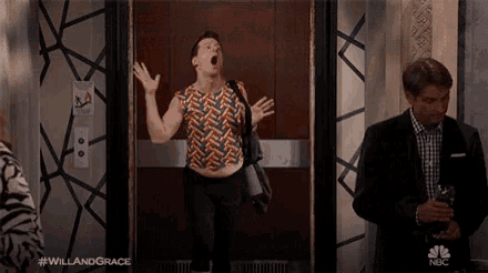 a man is yawning in an elevator while a man in a suit stands next to him .