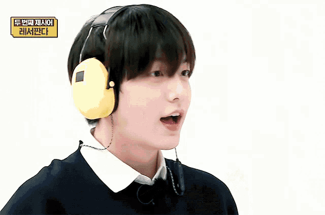 a young man wearing headphones and a sweater with a bear on it