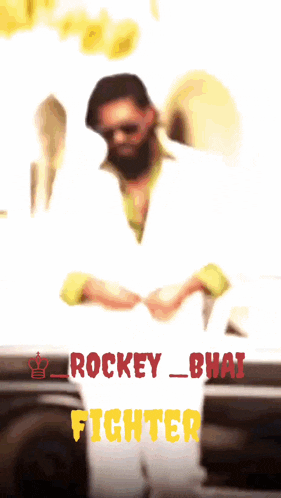 a man with a beard is standing in front of a white car with the words rockey_bhai fighter in red
