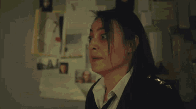 a woman in a black suit and tie looks shocked