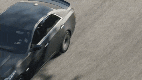 a car is driving down a road and the shadow of a tree is cast on the road