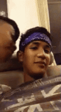 a man wearing a bandana is sitting next to another man on a plane .