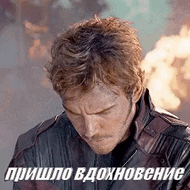 a man in a leather jacket is standing in front of a fire with a foreign language behind him .