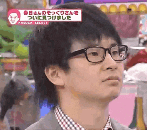 a man wearing glasses and a plaid shirt is looking at something
