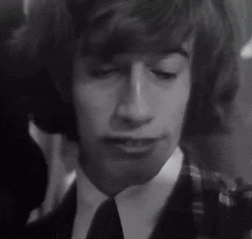 a black and white photo of a young man in a suit and tie with his eyes closed .