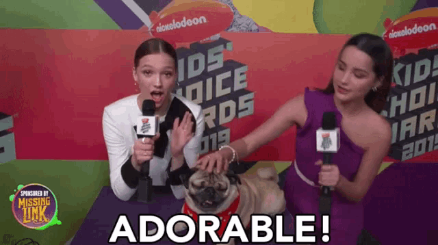 a pug dog is being interviewed by two women at a nickelodeon kids voice awards