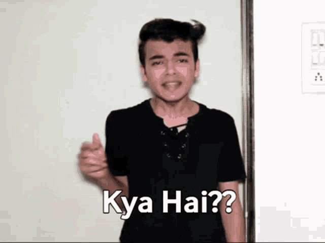 a young man stands in front of a door and says " kya hai "