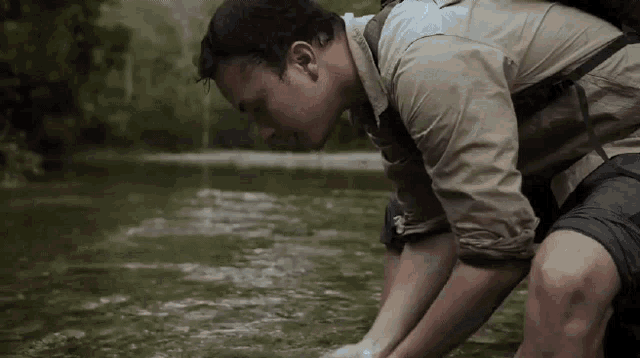 a man with a backpack is kneeling down in the water