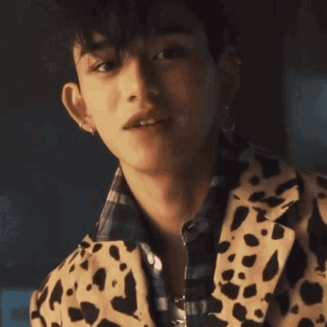 a close up of a man wearing a leopard print jacket and earrings .