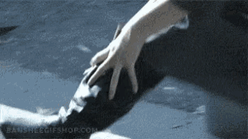 a person 's hand is touching a shark 's tail with the website bansheegifshop.com visible in the background