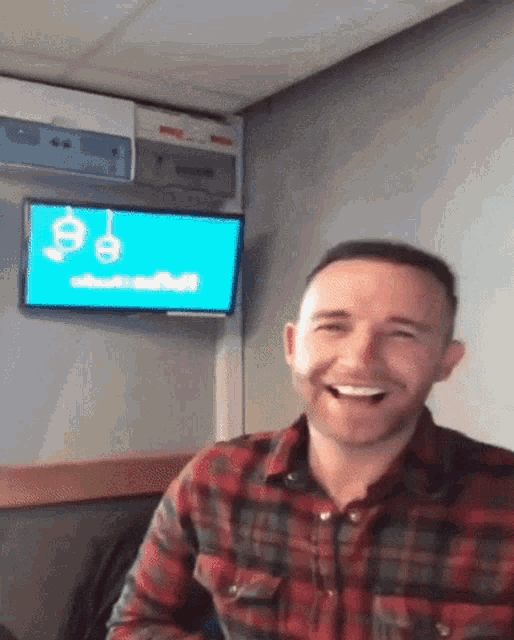 a man in a plaid shirt is laughing in front of a tv screen that says abstract
