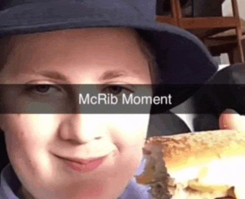 a person wearing a hat is holding a sandwich with the words mcrib moment on it
