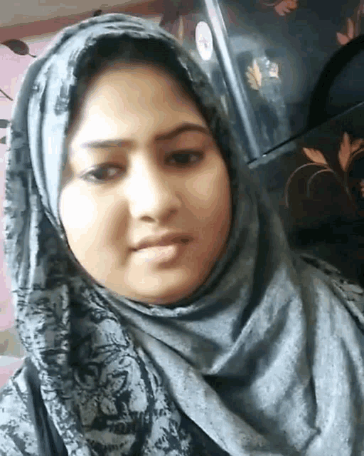 a woman wearing a hijab is taking a picture of herself .