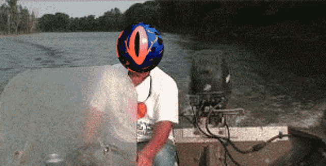 a man wearing a helmet with an eye on it is sitting on a boat