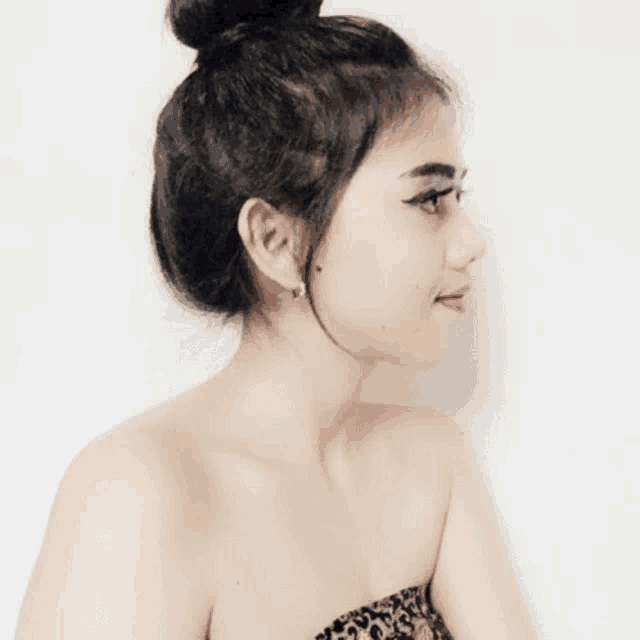 a woman with her hair in a bun is wearing a leopard print strapless top