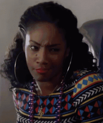a woman wearing hoop earrings and a necklace makes a funny face .