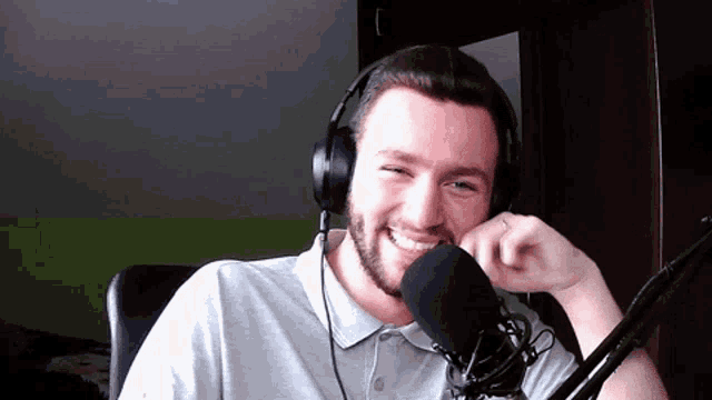 a man wearing headphones and a microphone smiles for the camera
