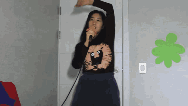 a woman is singing into a microphone with a cat on her shirt
