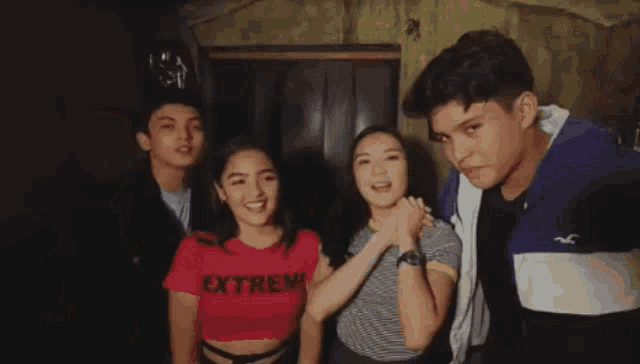 a group of young people are posing for a picture . one of the girls is wearing a red shirt that says extrem .
