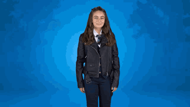 a girl wearing a leather jacket and tie is waving her hand