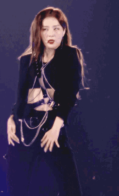 a woman wearing a black crop top and black pants is dancing on a stage