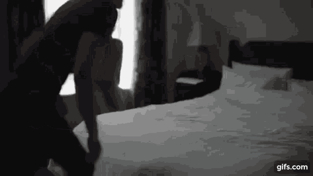 a man is standing on a bed in a black and white photo .