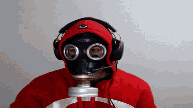 a man wearing a gas mask and headphones is holding a microphone