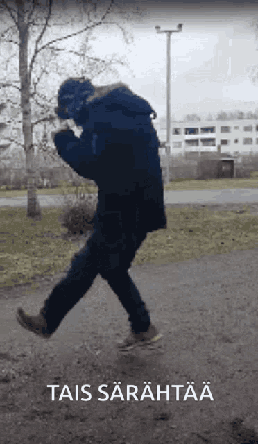 a man in a black jacket is walking down a path with a sign that says " tai sarahtaa "