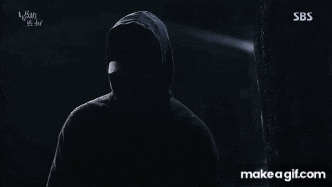 a man in a hooded sweatshirt is spraying water on a tree .