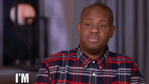 a man in a plaid shirt is making a funny face and says i 'm