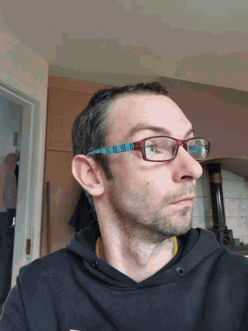a man wearing glasses has a tattoo on his neck and a black shirt