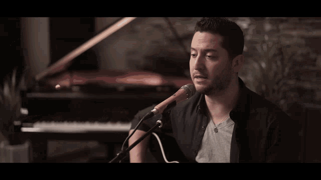 a person playing an acoustic guitar with a reflection of a man behind them