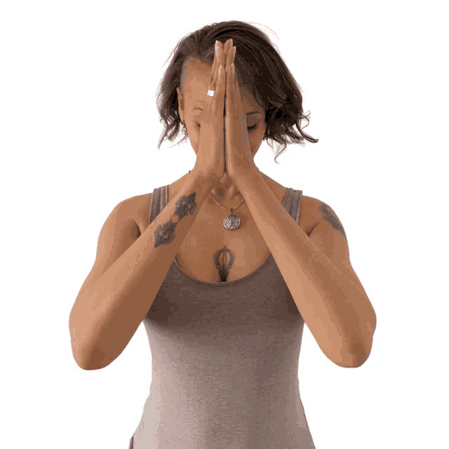 a woman with a tattoo on her chest holds her hands together in prayer