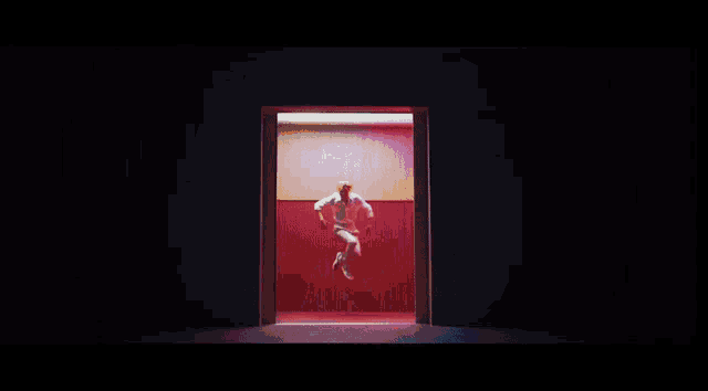 a man is dancing in front of a red wall in a dance studio .