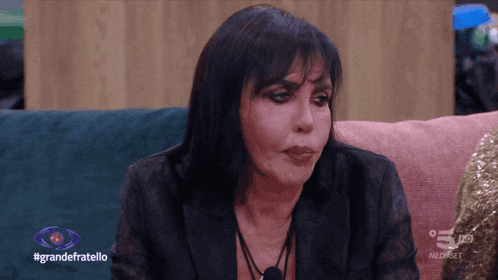 a woman sitting on a couch with the words grandefratello on the bottom left