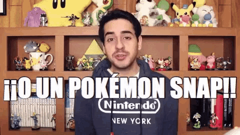a man wearing a nintendo new york sweatshirt is standing in front of a shelf full of toys