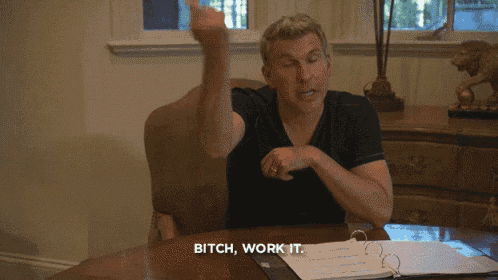 a man sitting at a desk says " bitch work it " in front of a binder