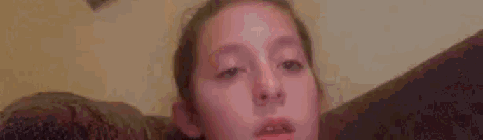 a woman is laying on a couch with her tongue out and licking her lips .