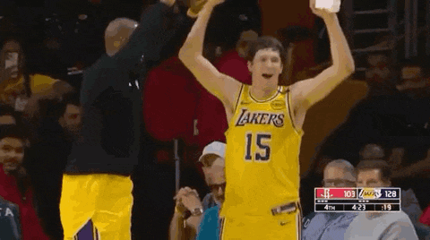 a basketball player wearing a lakers jersey is holding a trophy in his hand .