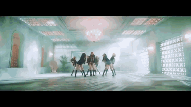 a group of young women are dancing in a room with a chandelier