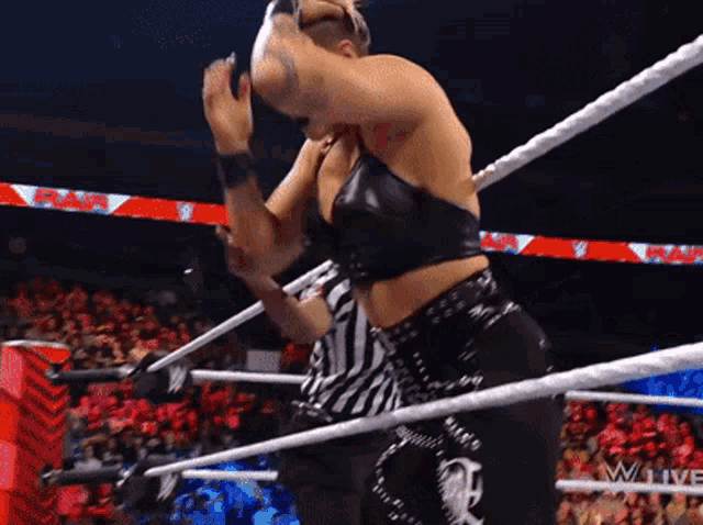 a woman is wrestling in a ring while a referee watches .