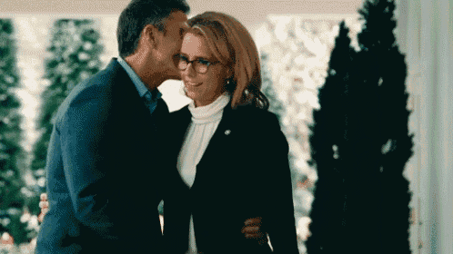a man is kissing a woman on the forehead while standing next to her .