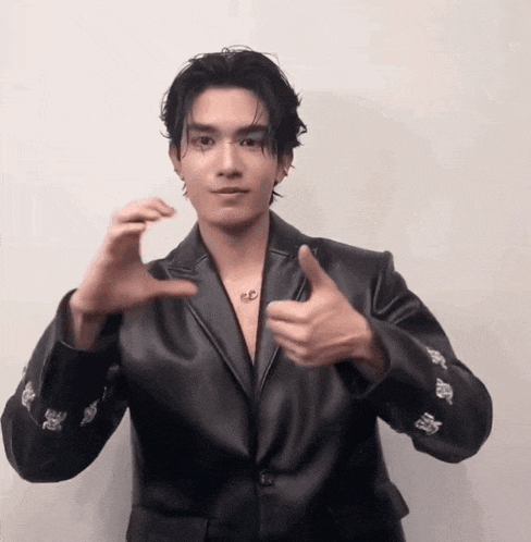 a man in a black leather jacket is giving a thumbs up sign