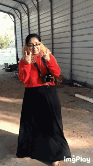a woman in a red sweater and black skirt is giving the middle finger while holding a camera