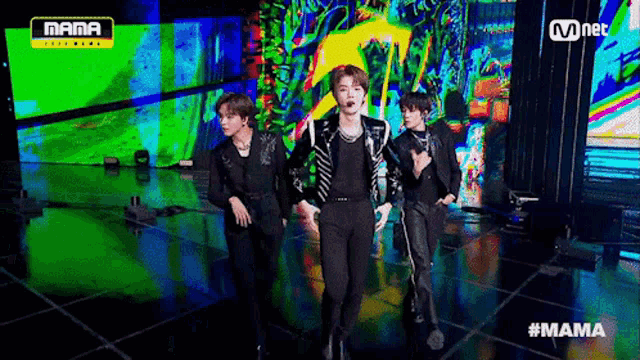 a group of men are dancing on a stage in front of a colorful screen .