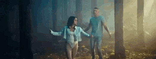 a man and a woman are holding hands in a forest .