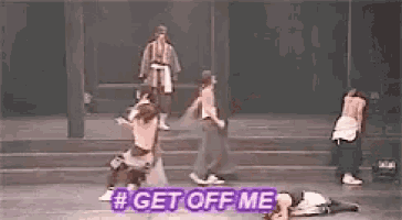 a group of people are dancing on a stage and one of them is laying on the ground .