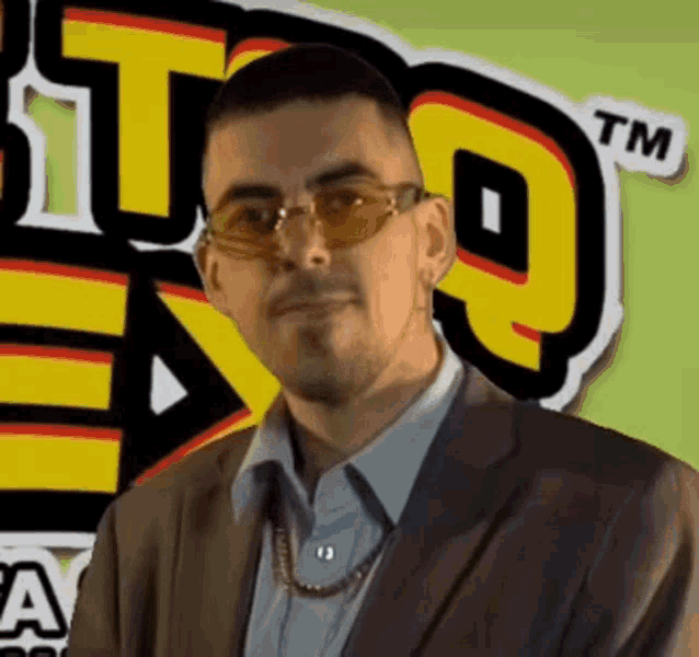 a man wearing sunglasses stands in front of a tm logo