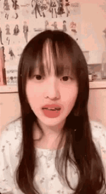 a girl with long hair and bangs is talking to the camera .
